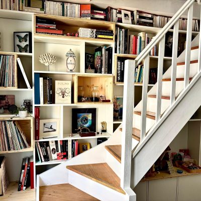 Bibliothèque derrière escalier existant. Mélaminé blanc et épicéa. Bandeaux Led dans les niches.