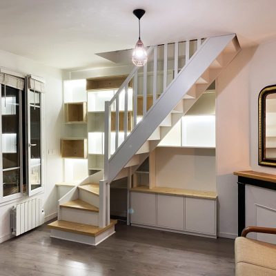 Bibliothèque derrière escalier existant. Mélaminé blanc et épicéa. Bandeaux Led dans les niches.